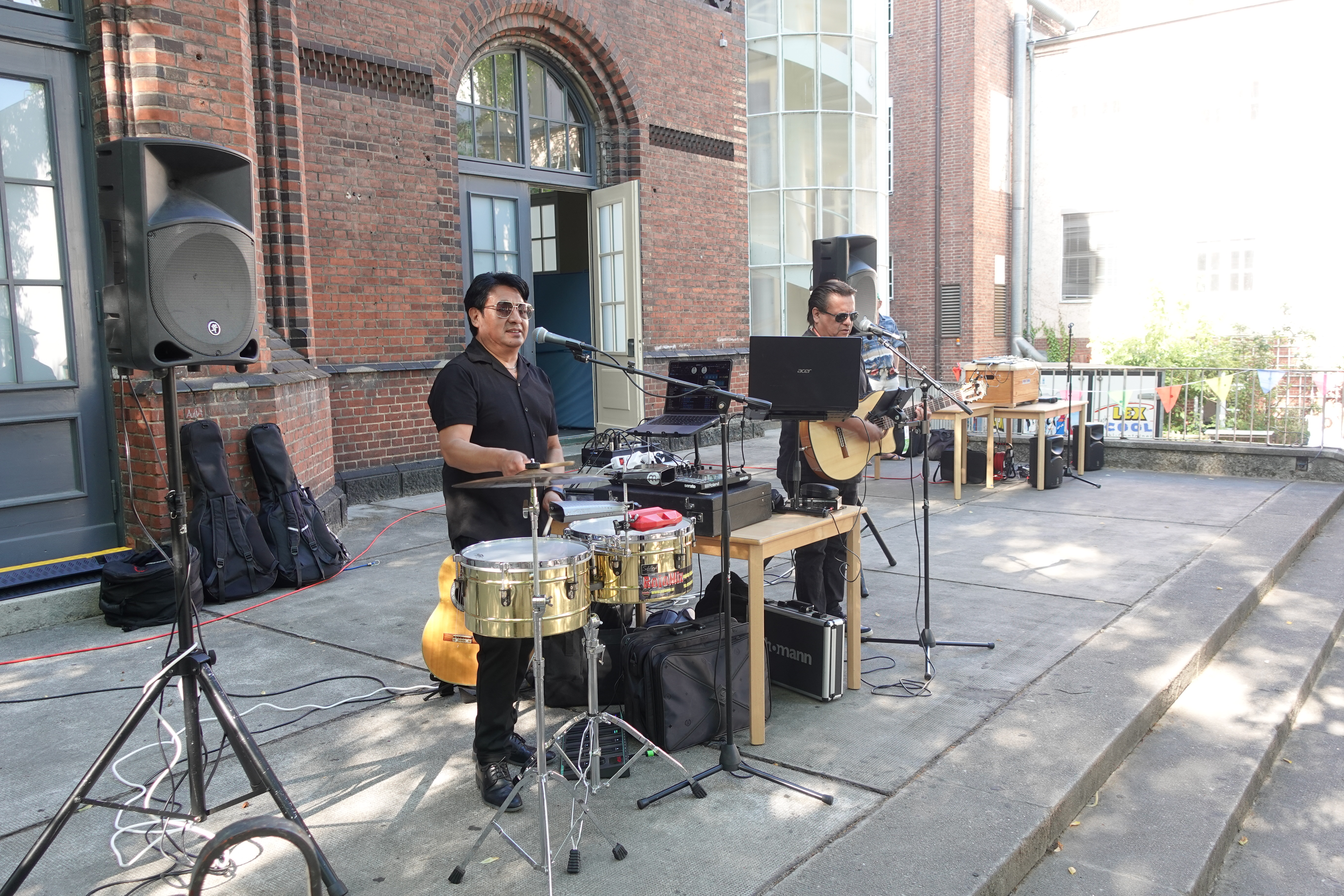 Band spielt beim Sommerfest. Zwei Männer spielen Schlagzeig und Gitarre und singen. 