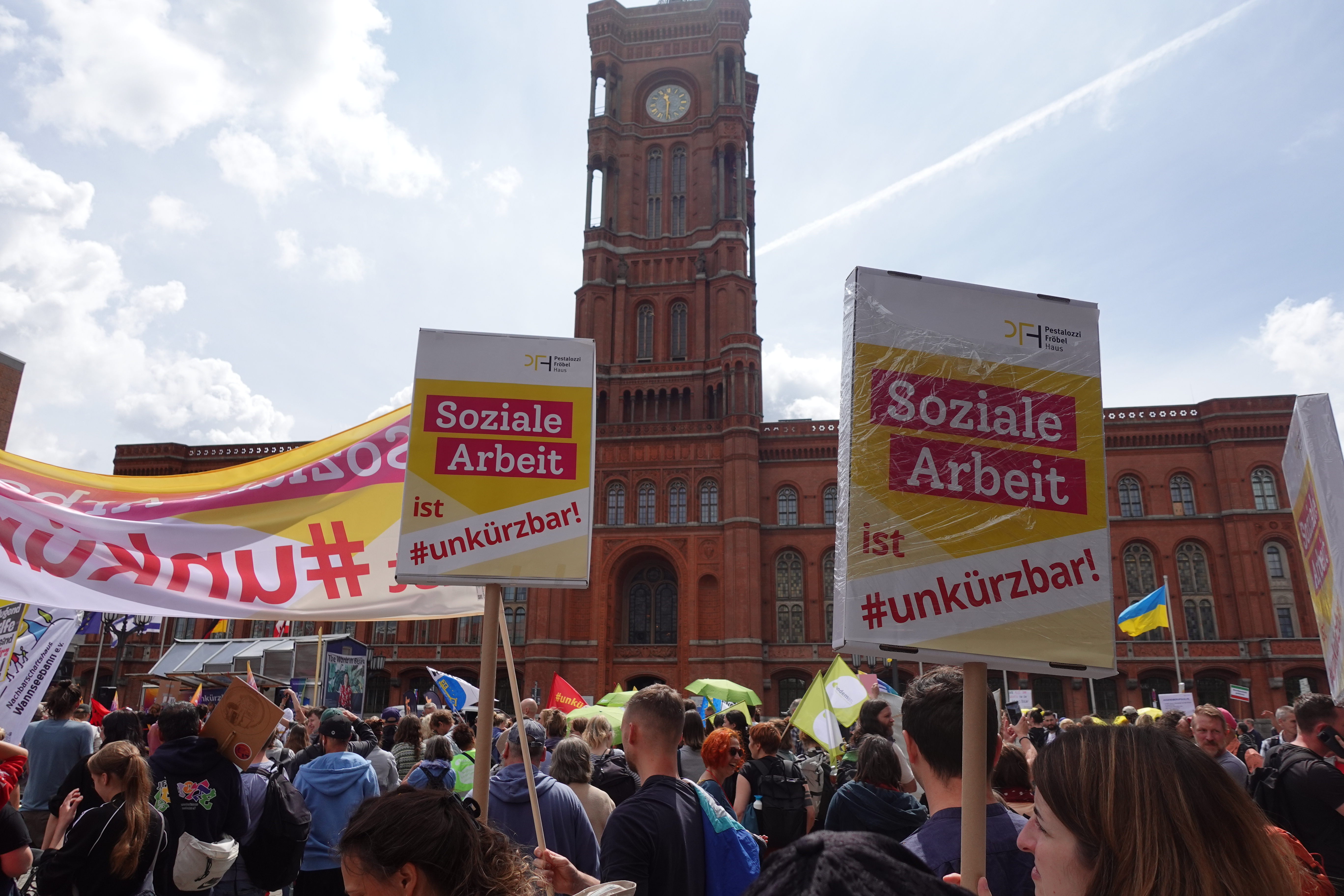 Soziale Arbeit ist #unkürzbar! Mitarbeiter*innen des PFH demonstrieren vor dem Roten Rathaus mit Schildern.