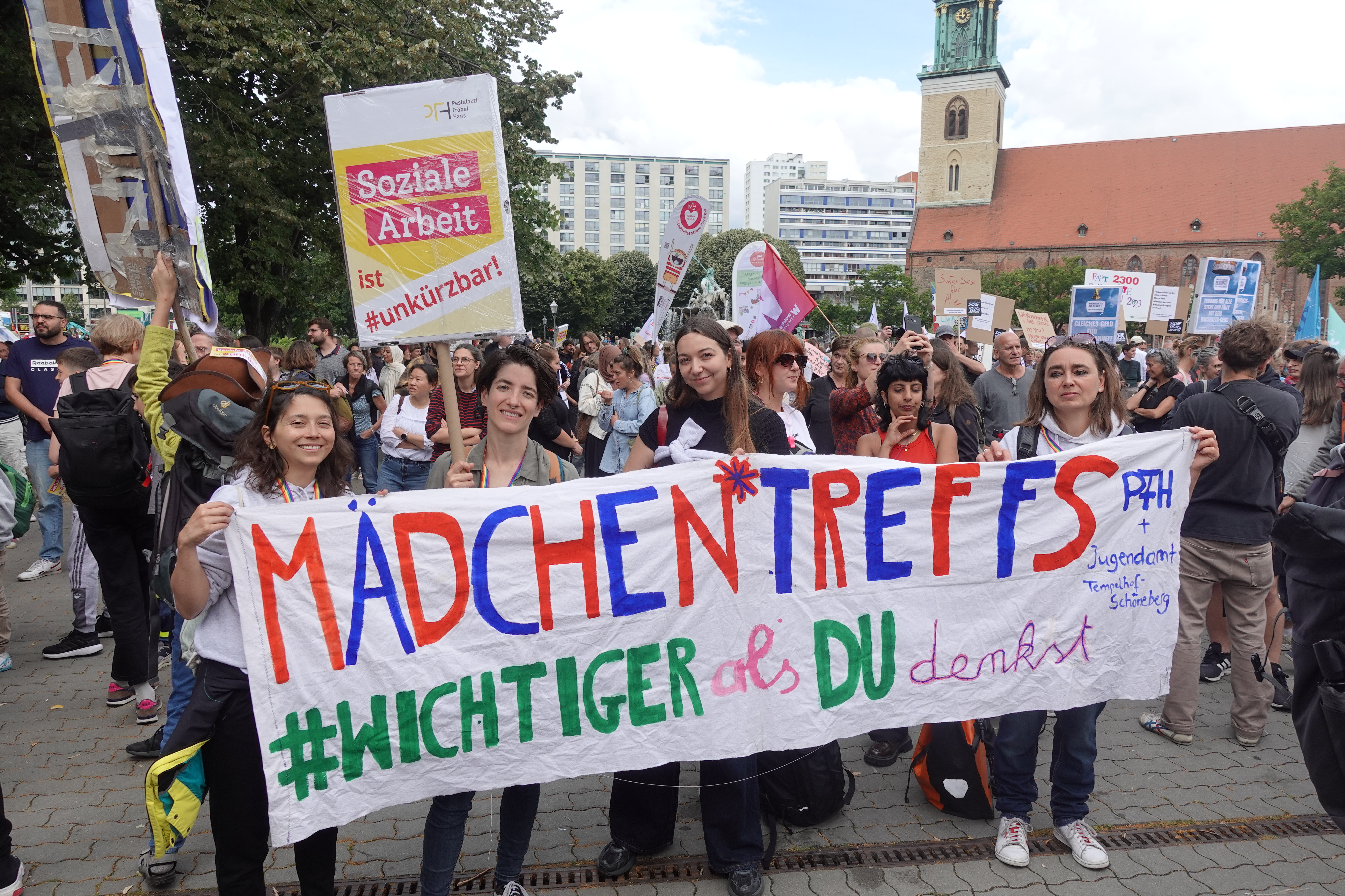 Mädchen*treffs sind wichtiger als du denkst! Mitarbeiter*innen des PFH (Café Pink) demonstrieren vor dem Roten Rathaus mit Schildern.