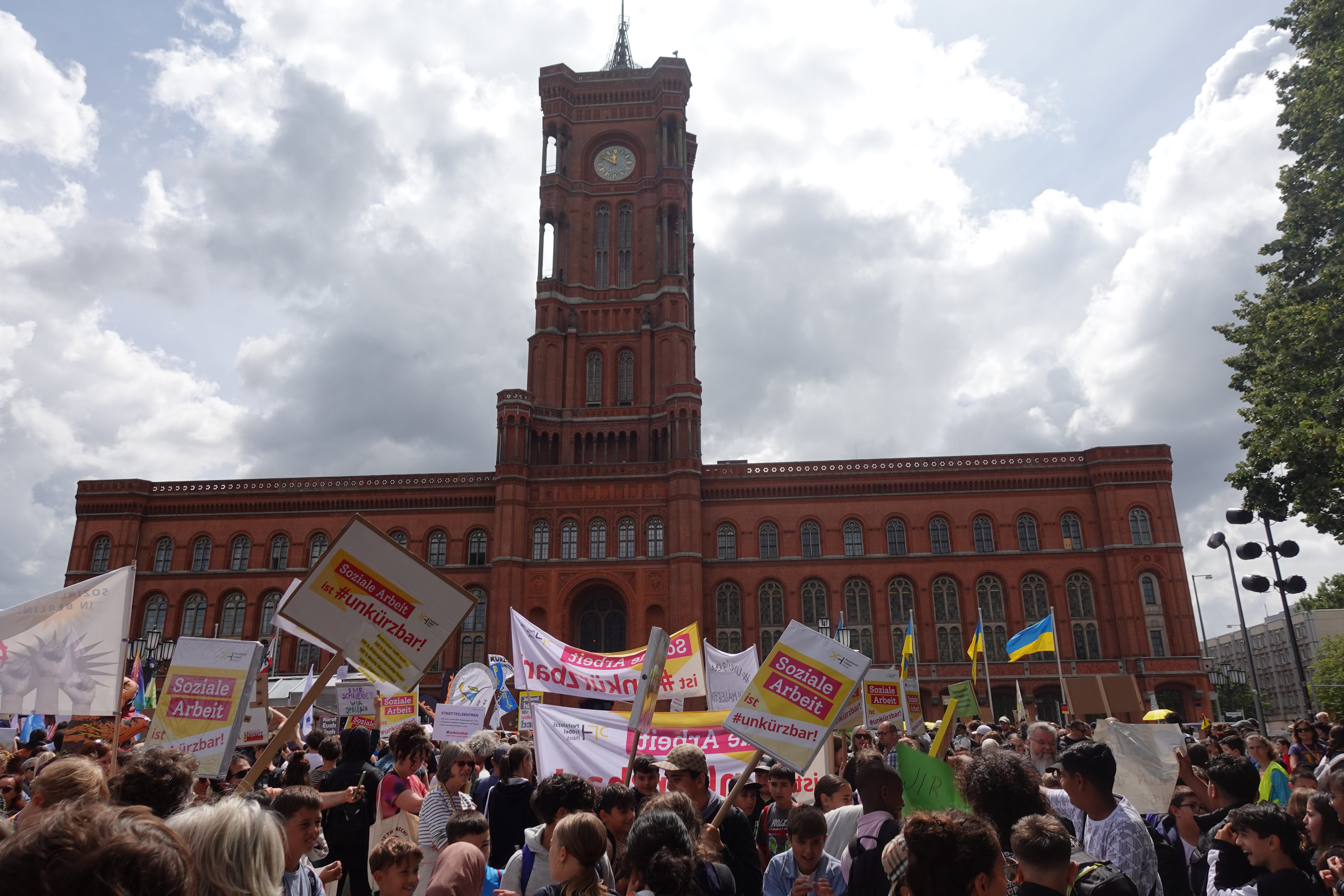 Soziale Arbeit ist #unkürzbar! Mitarbeiter*innen des PFH demonstrieren vor dem Roten Rathaus mit Schildern.