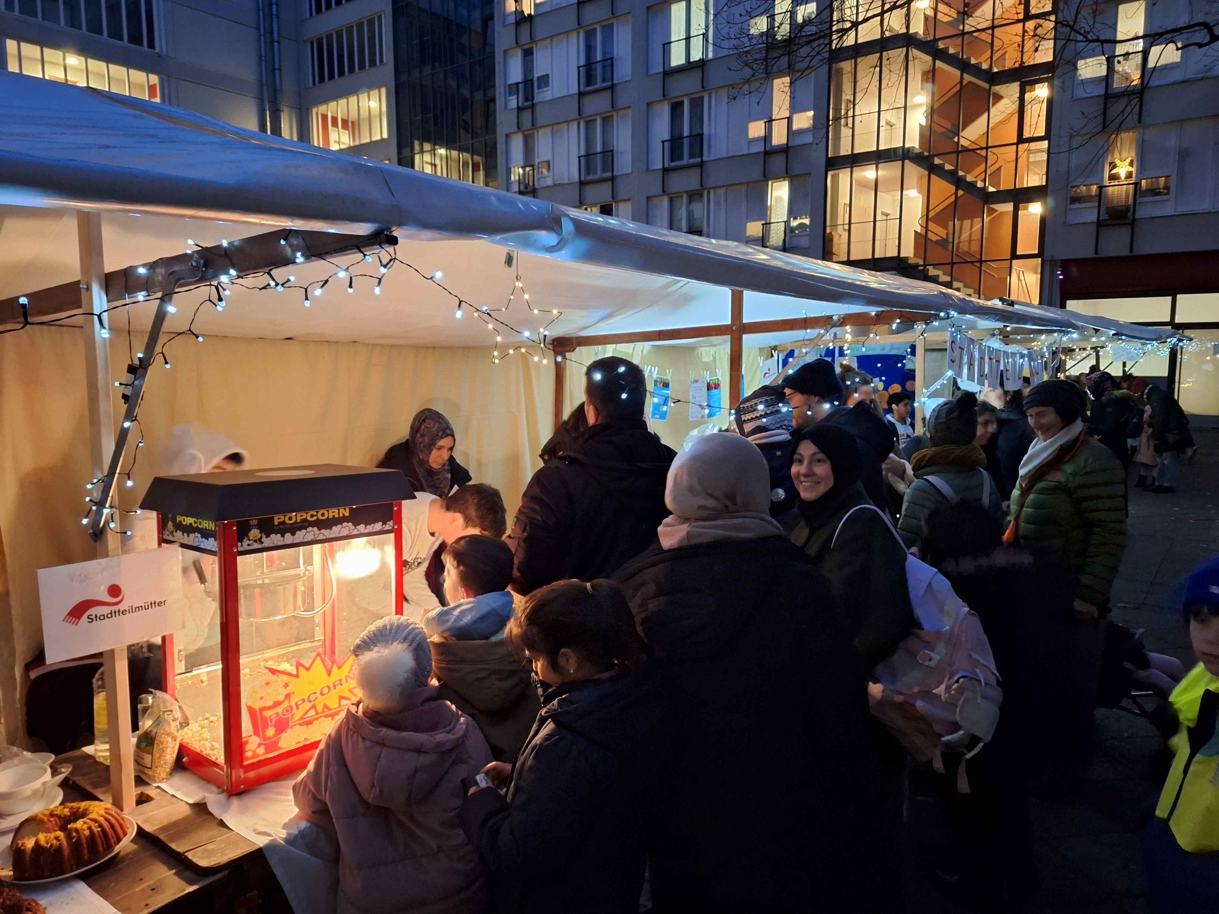 Viele Menschen warten am Popcornstand beim Wintermarkt am Pallasseum