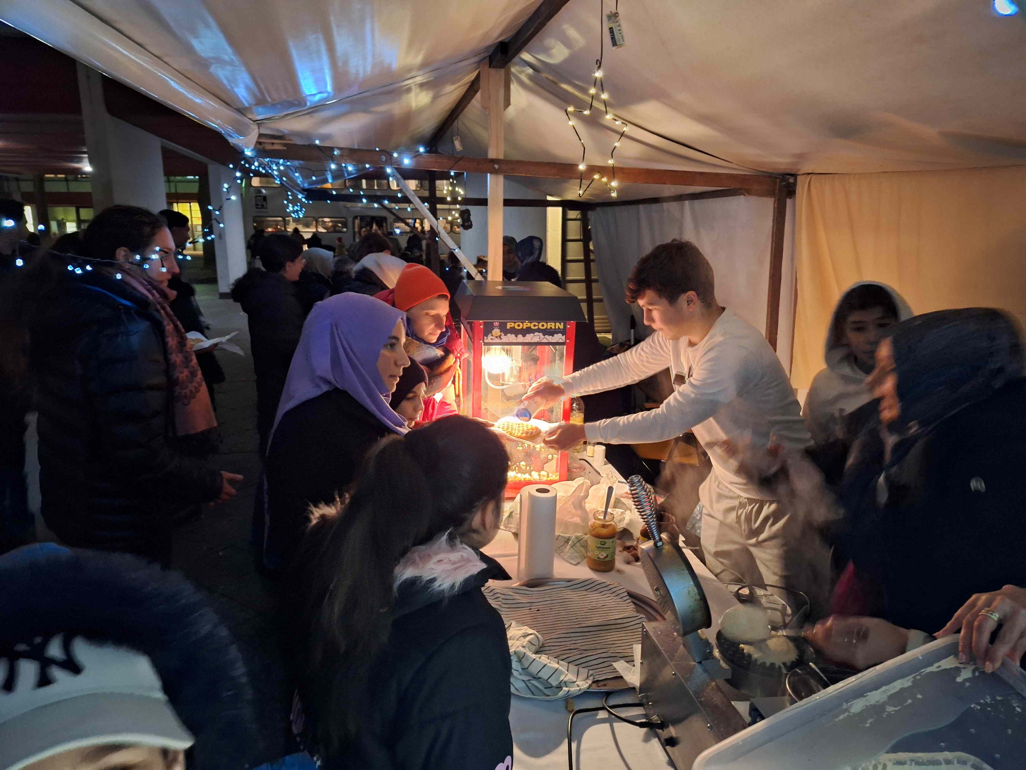 Viele Menschen warten am Popcornstand beim Wintermarkt am Pallasseum