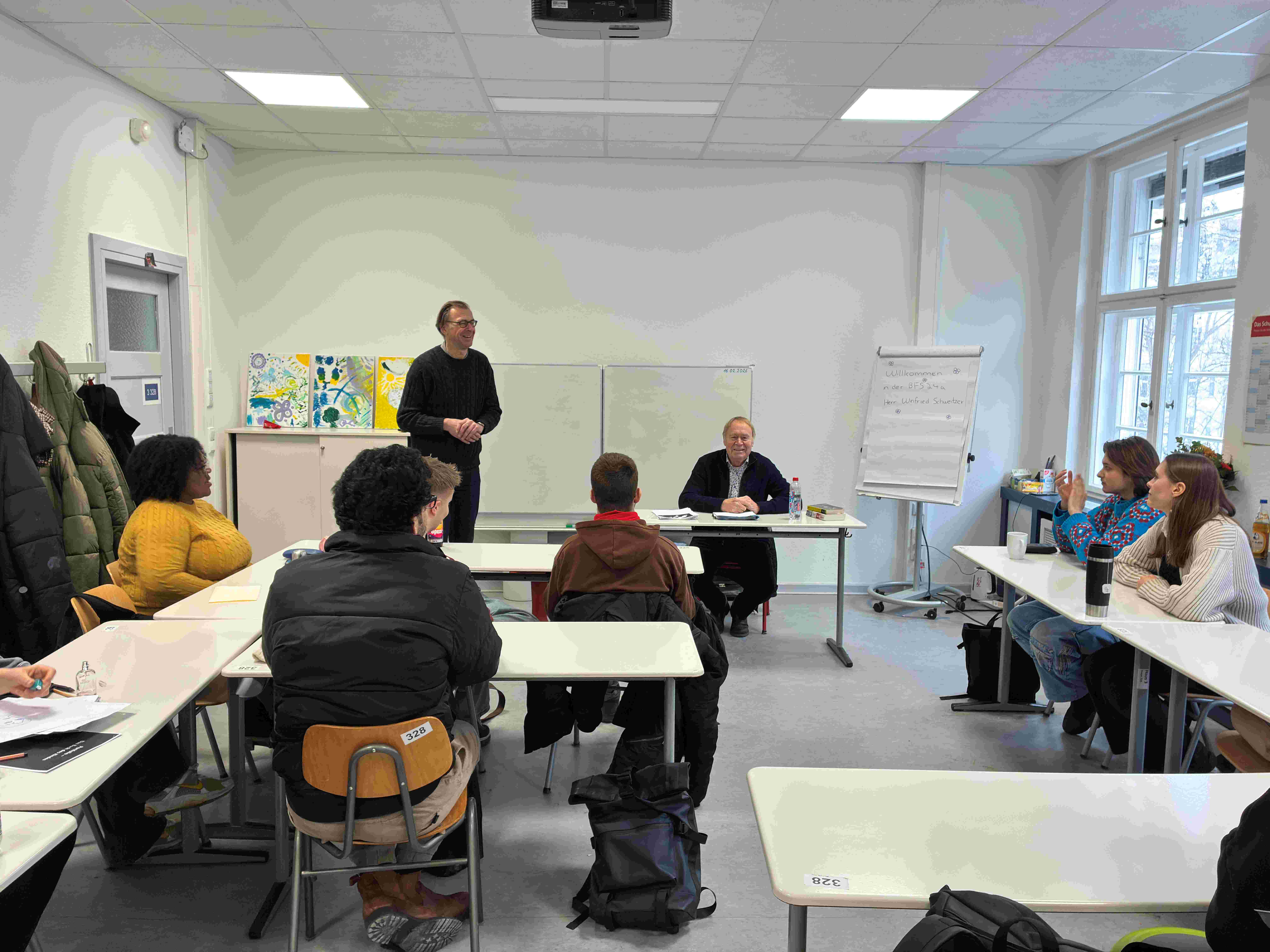 Schulleiter Jochen Knopp begrüßt Zeitzeuge Winfried Schweitzer vor der Schulklasse