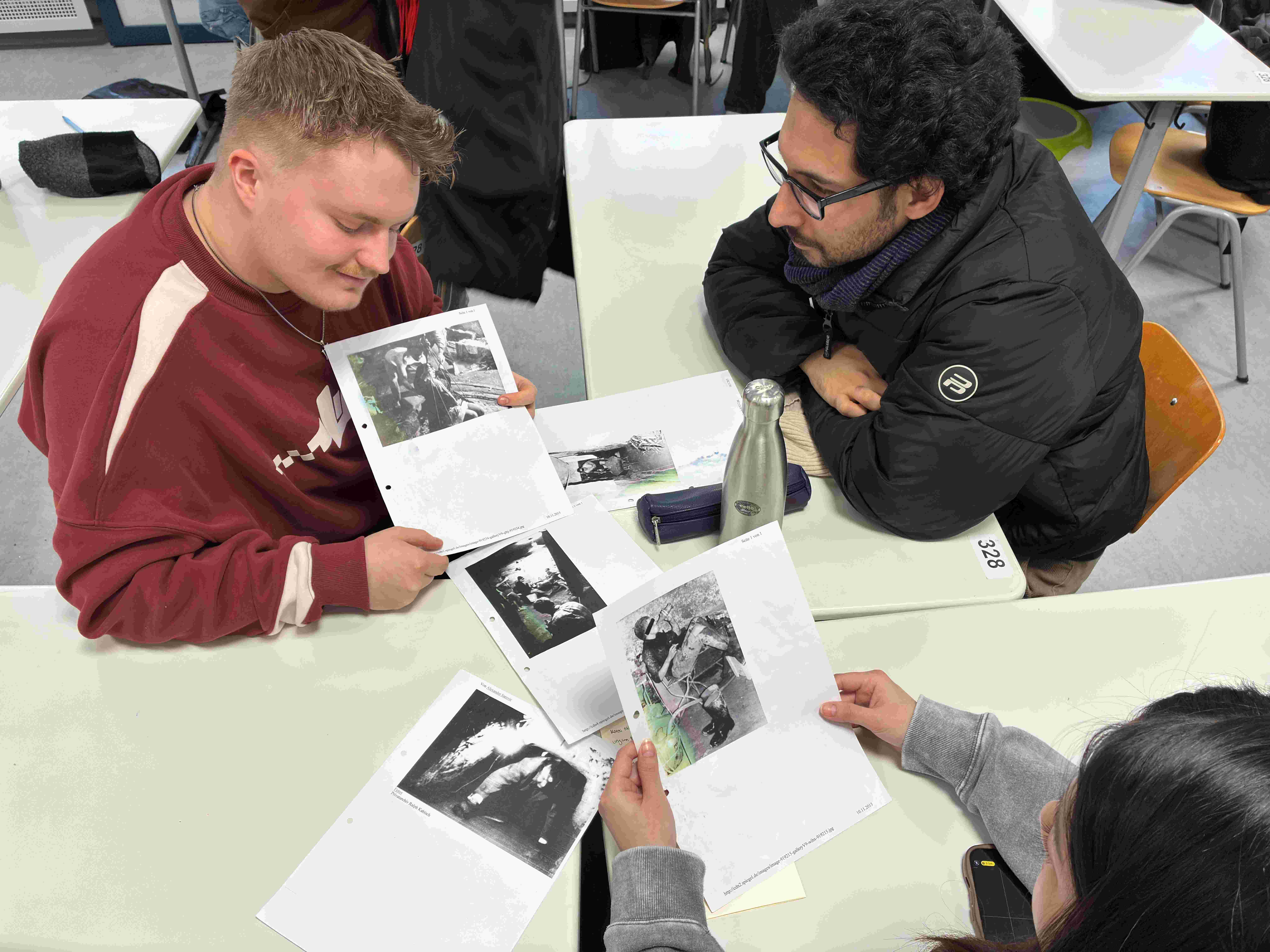 Schüler*innen studieren ausgedruckte Schwarz-Weiß-Fotos
