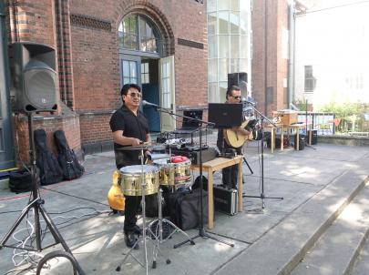 Band spielt beim Sommerfest. Zwei Männer spielen Schlagzeig und Gitarre und singen. 