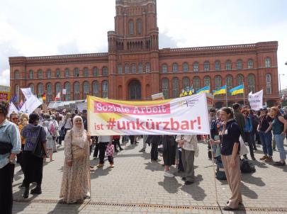 Soziale Arbeit ist #unkürzbar! Mitarbeiter*innen des PFH demonstrieren vor dem Roten Rathaus mit Schildern.