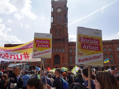 Soziale Arbeit ist #unkürzbar! Mitarbeiter*innen des PFH demonstrieren vor dem Roten Rathaus mit Schildern.
