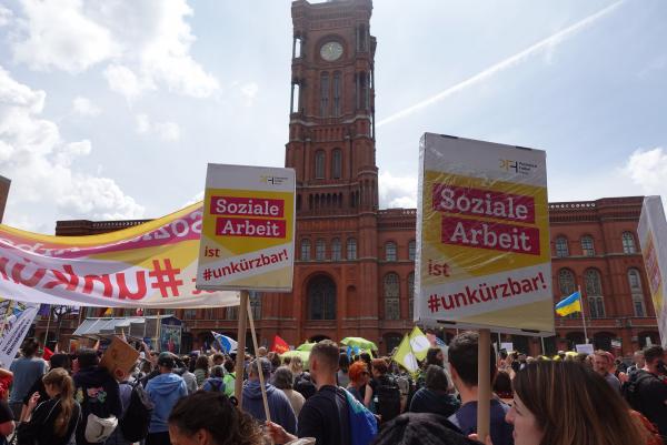 Soziale Arbeit ist #unkürzbar! Mitarbeiter*innen des PFH demonstrieren vor dem Roten Rathaus mit Schildern.