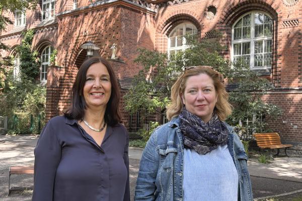 Henriette Harms und Simone Paganini stehen vor der Schule des PFH. Im Hintergrund ist das Backsteingebäude.