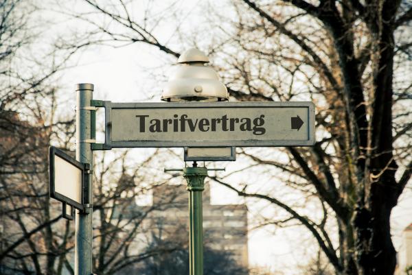 Ein berliner Straßenschild auf dem "Tarifvertrag" steht und ein Pfeil abgebildet ist