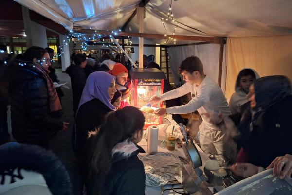Viele Menschen warten am Popcornstand beim Wintermarkt am Pallasseum