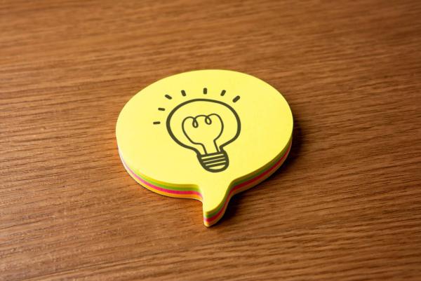 Eine Sprechblase und ein handgezeichnetes Symbol einer Glühbirne.