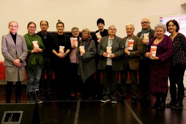 Gruppenfoto zur Verleihung der Ehrenamtskarte: Zwölf Personen stehen in einer Reihe nebeneinander und lächeln. Einige halten eine Karte in der Hand. 