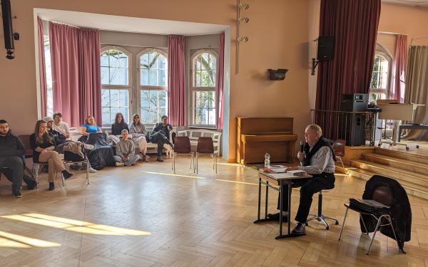 Schüler*innen der Berufsschule im PFH hören Winfried Schweitzer beim Erzählen seiner Geschichten zu.