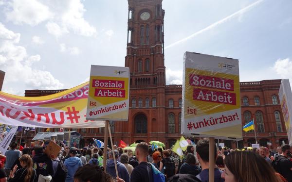 Soziale Arbeit ist #unkürzbar! Mitarbeiter*innen des PFH demonstrieren vor dem Roten Rathaus mit Schildern.