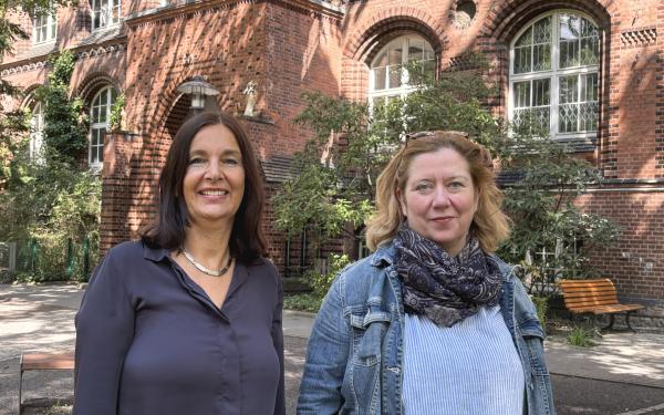 Henriette Harms und Simone Paganini stehen vor der Schule des PFH. Im Hintergrund ist das Backsteingebäude.