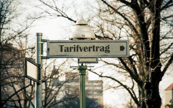 Ein berliner Straßenschild auf dem "Tarifvertrag" steht und ein Pfeil abgebildet ist
