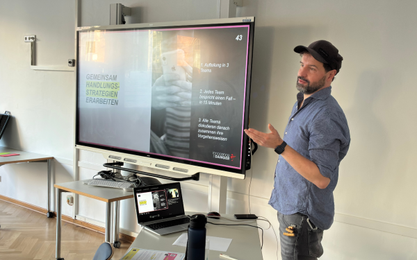 Ein Mann steht als Referent neben einer Präsentation und spricht.