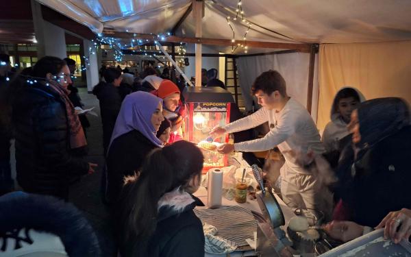 Viele Menschen warten am Popcornstand beim Wintermarkt am Pallasseum